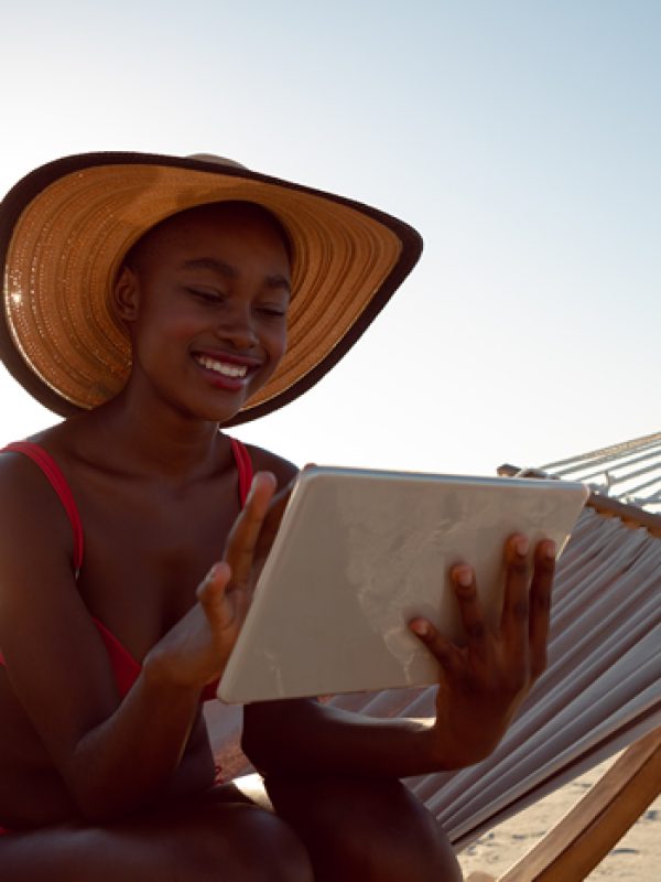 woman-using-digital-tablet-while-relaxing-hammock-beach